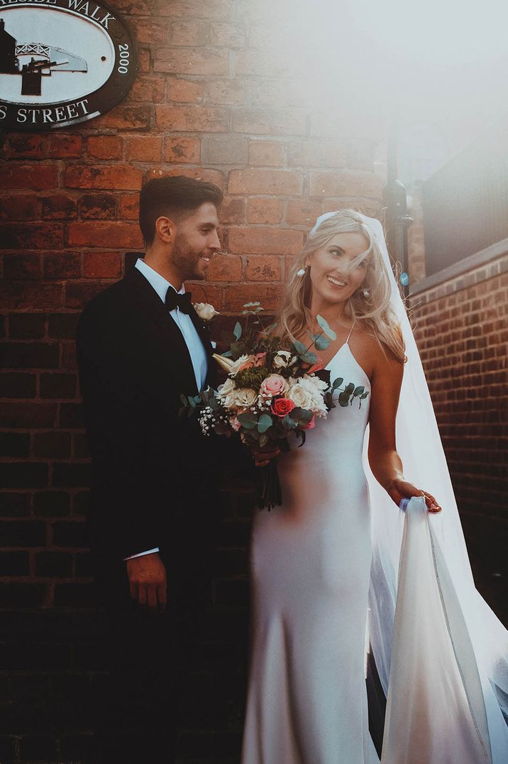 Bride in white halter neck satin wedding dress with groom at modern chic wedding 