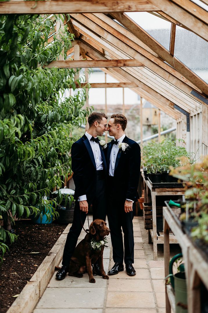 Two grooms wearing tuxedos at Deer Park country house wedding venue with their pet dog as a dog of honour 