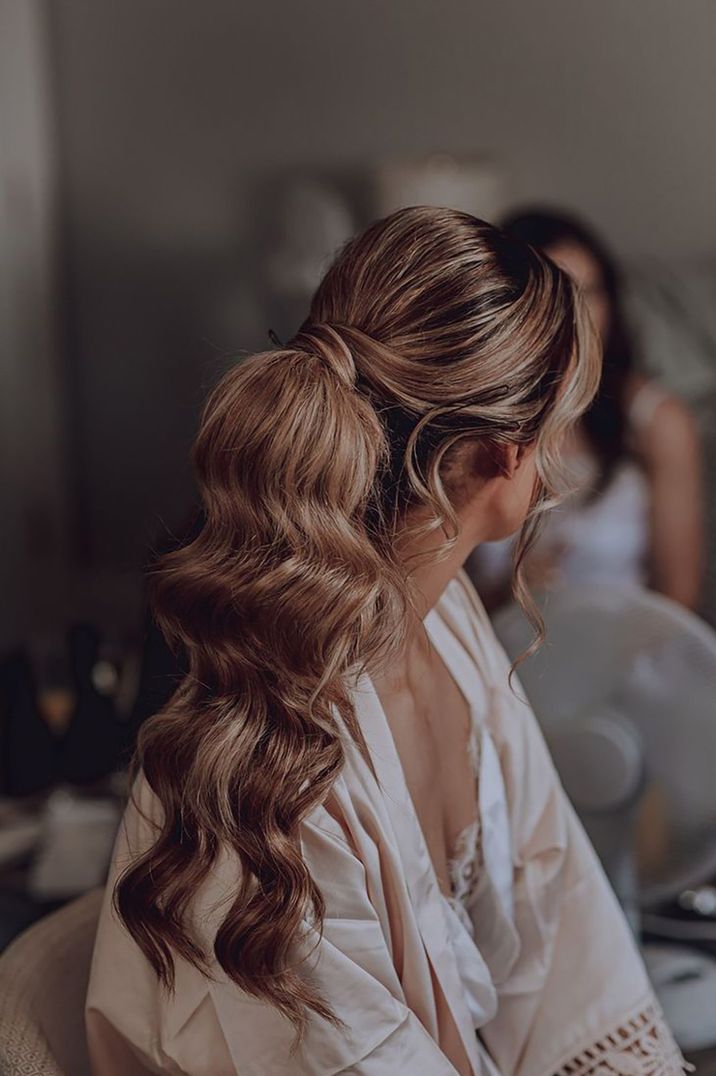 Bride wearing wavy ponytail hairstyle for wedding day 