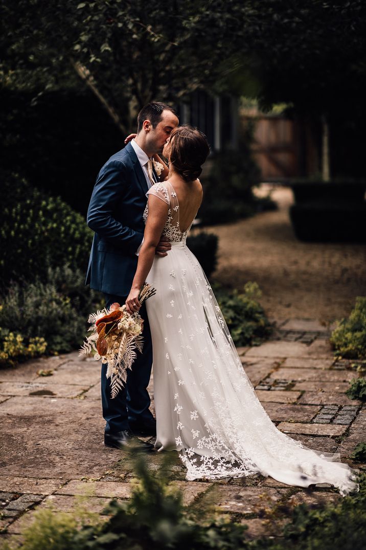 Bride in a Rime Arodaky wedding dress with lace train holding a neutral anthurium wedding bouquet 