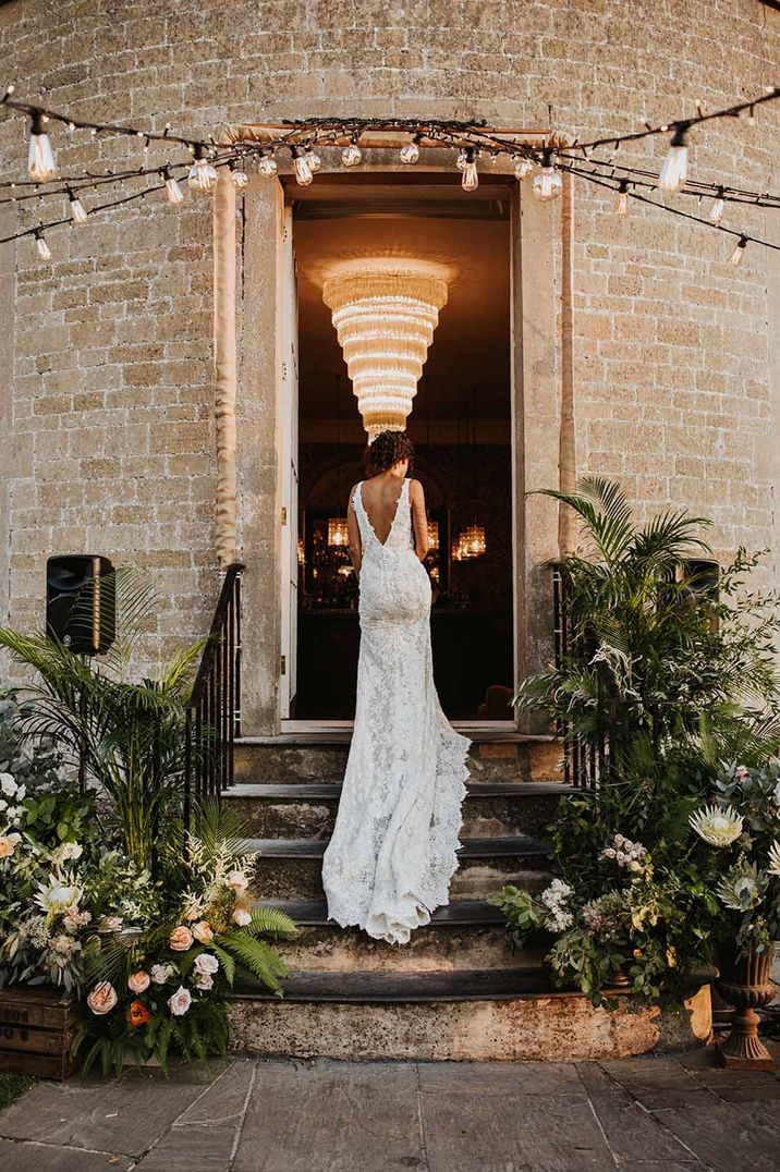 Bride in Pronovias wedding dress walking up the flower decorated steps at her traditional wedding