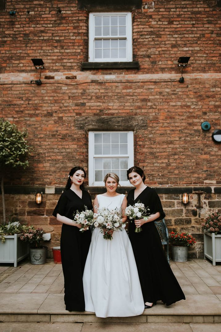 Bridesmaids wear long black bridesmaid dresses with batwing sleeves 