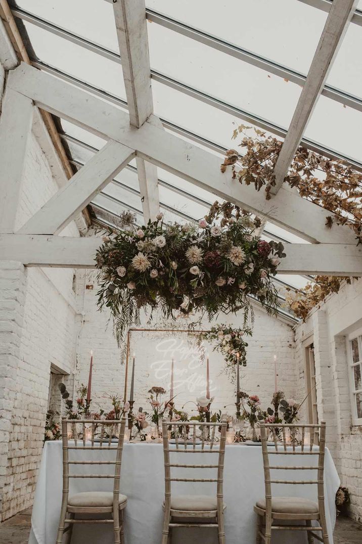 Suspended rose, peony and dried flower floral decor hanging over neutral wedding tablescape at Garthmyl Hall Shropshire glasshouse wedding venue 