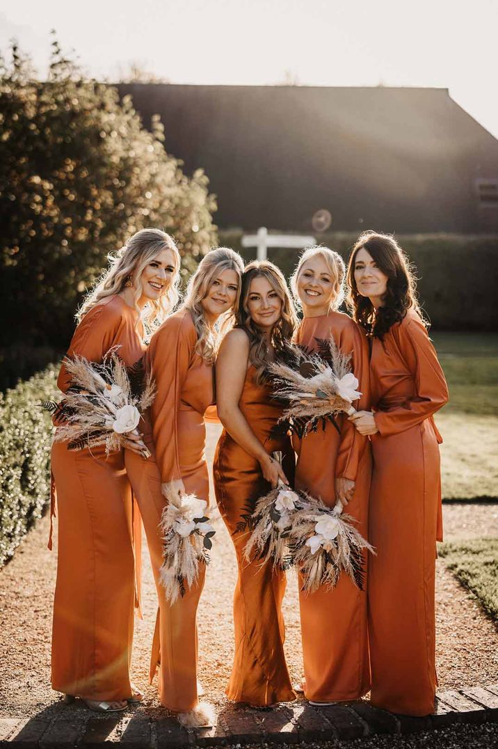 Bridesmaids in mismatched burnt orange bridesmaid dresses with pampas grass bouquets 