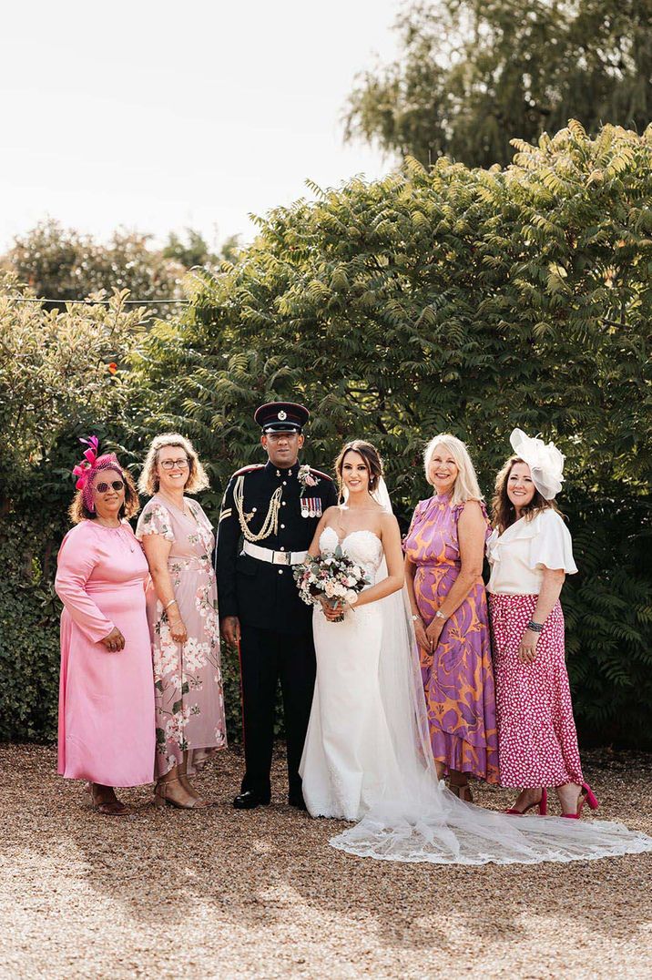 Wedding guests wearing pink dresses posing with the bride and groom