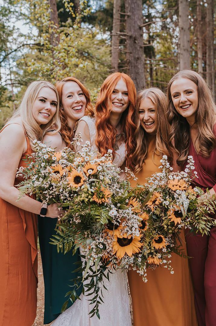 Bride and bridesmaids holding sunflower and gypsophila wedding bouquets for late summer wedding 