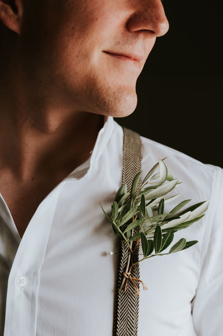 Groom in a white grandad collar shirt, dog tooth braces and foliage buttonhole 