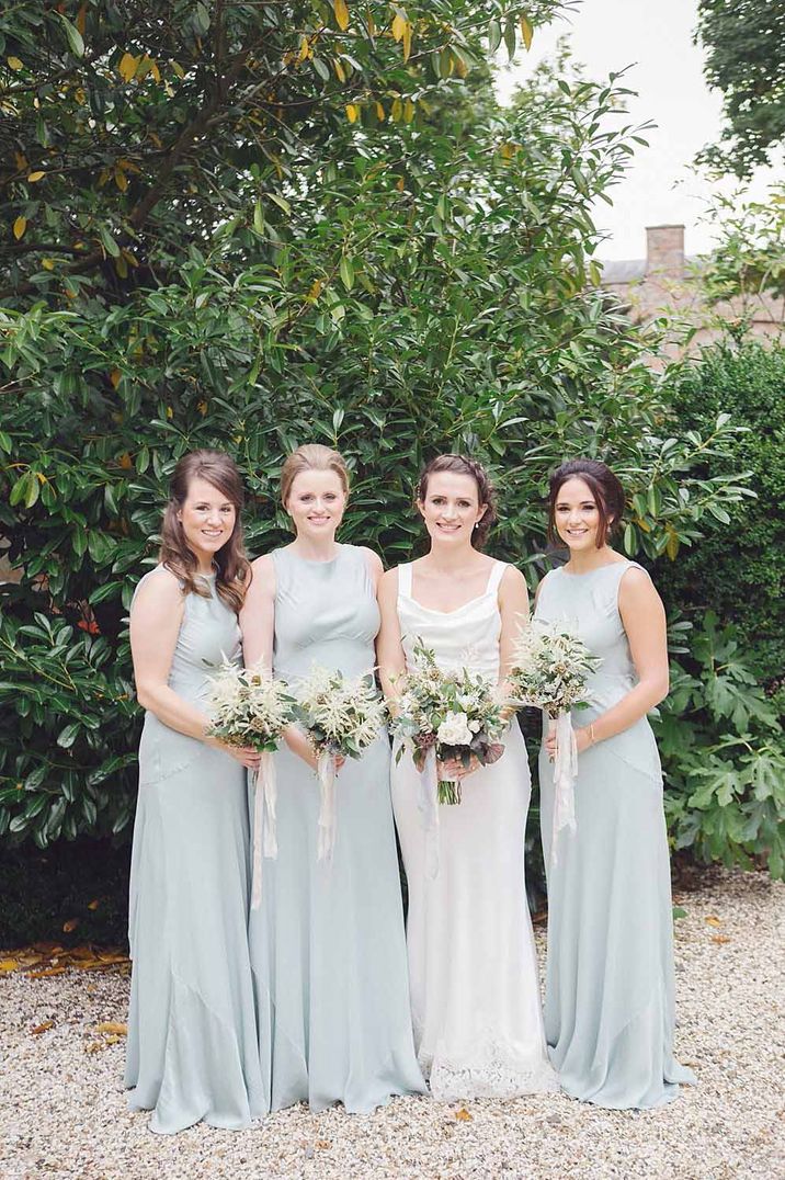 Bridesmaids in mint green boat neck bridesmaid dresses with bride in cowl neck wedding dress 