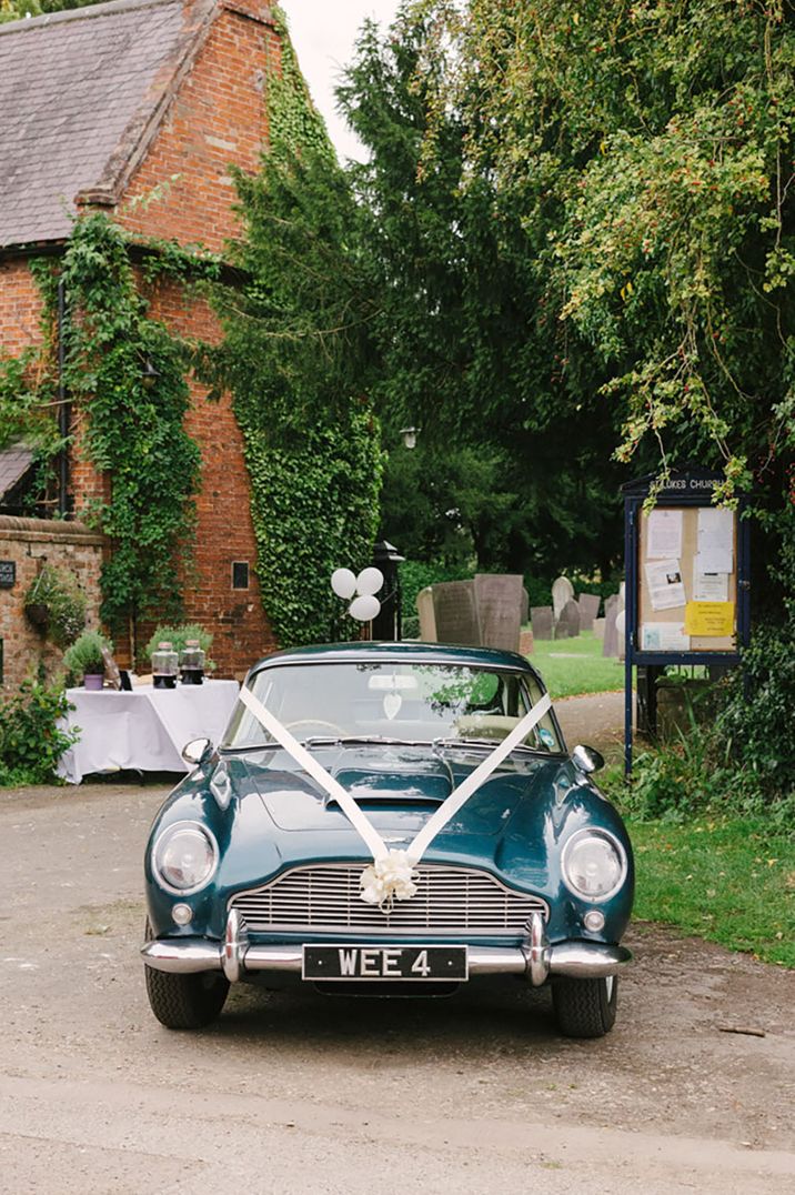 Classic blue wedding car with white ribbon decorations tied at the front