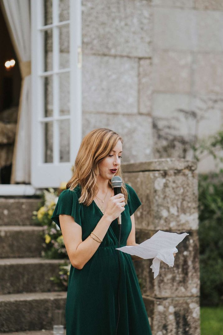 Maid of honour in dark green short sleeve dress giving speech 