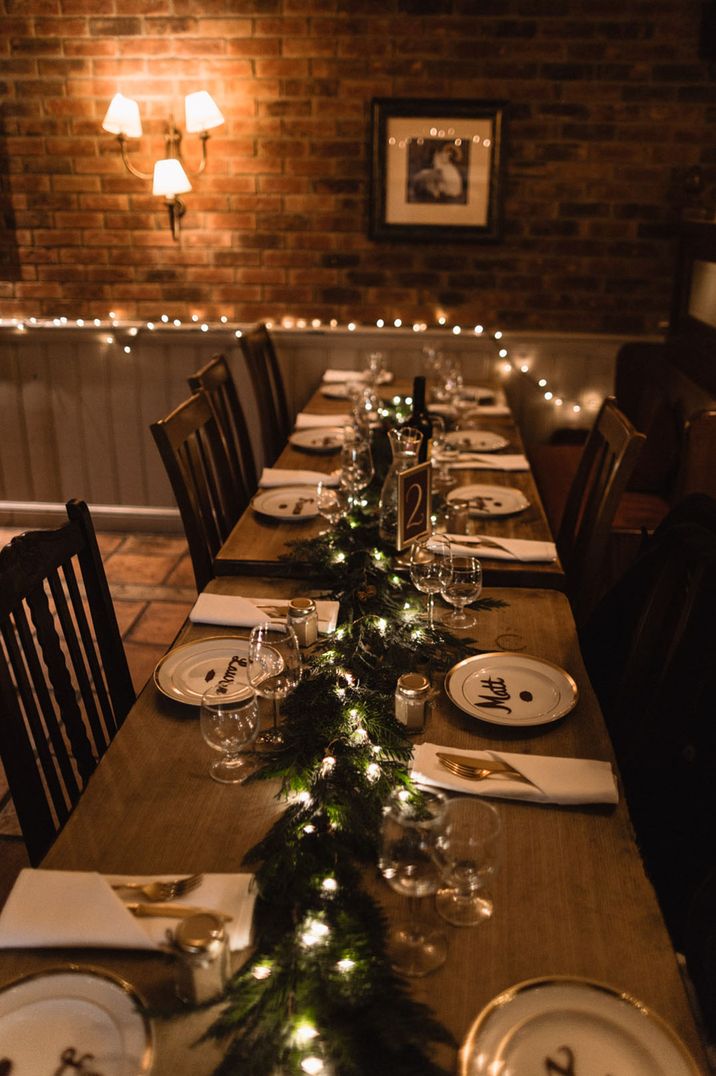 Wedding table setting for a winter wedding with a festive garland and fairy lights