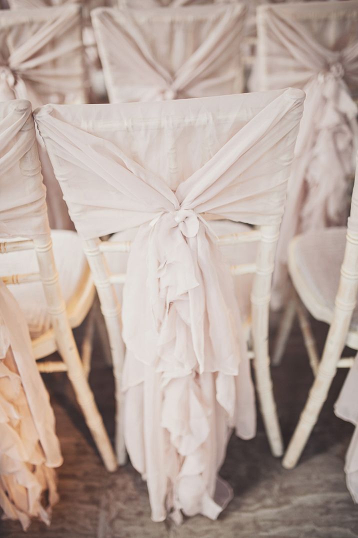 White wedding chair decorated with an off white ruffle bow chair sash for the wedding ceremony 