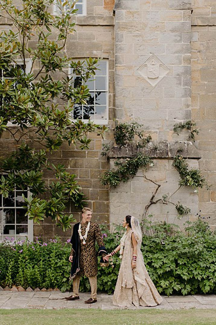 Country house wedding for multicultural couple with the bride and groom in brown and gold wedding outfits 