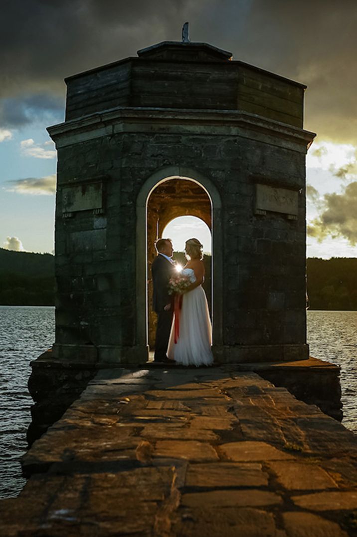 The bride and groom pose for their wedding photos with a view of the sea 