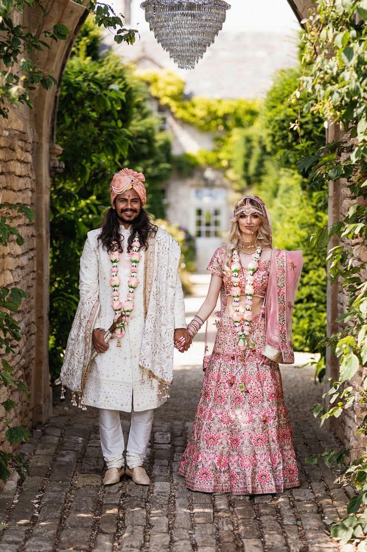 Bride and groom in pink and gold traditional Indian outfits at The Lost Orangery, Euridge Manor 