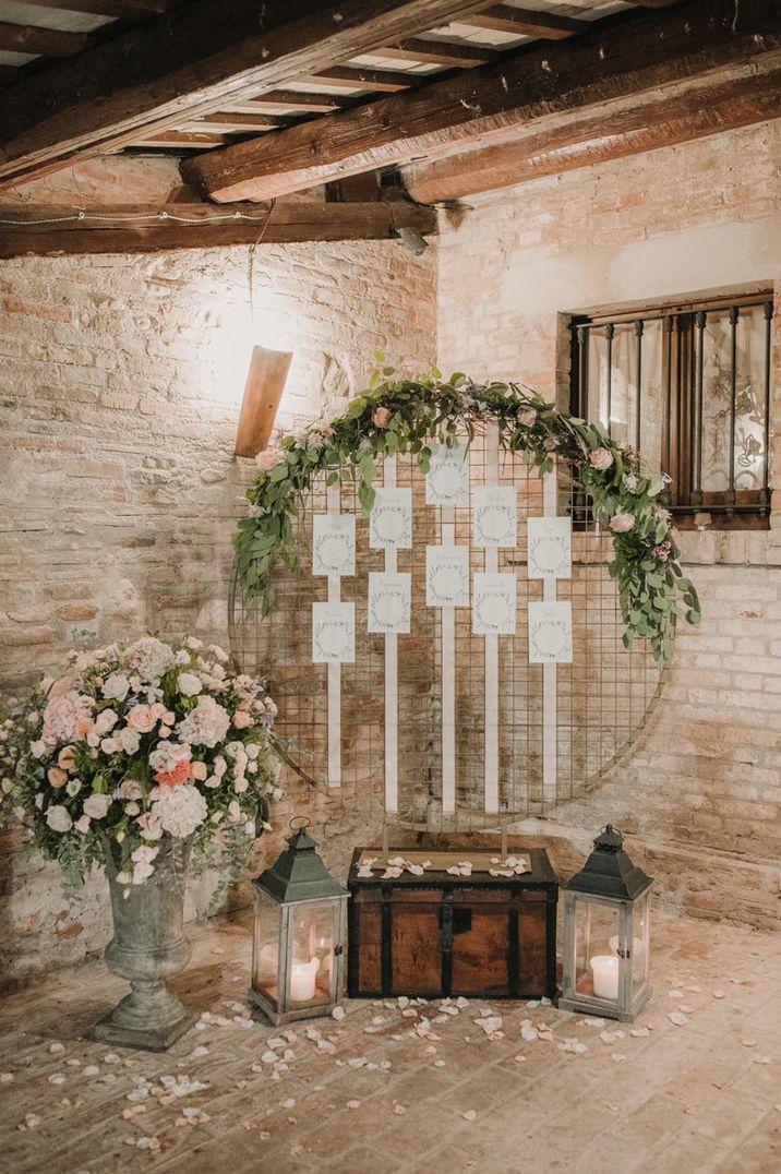 Large hoop wedding seating chart with pink flowers and foliage decor 