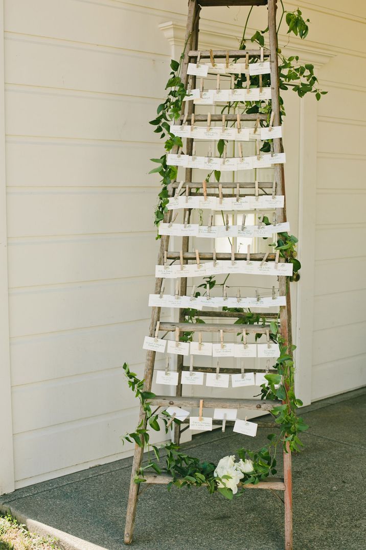 Wooden ladder with peg table plan decorated with greenery 