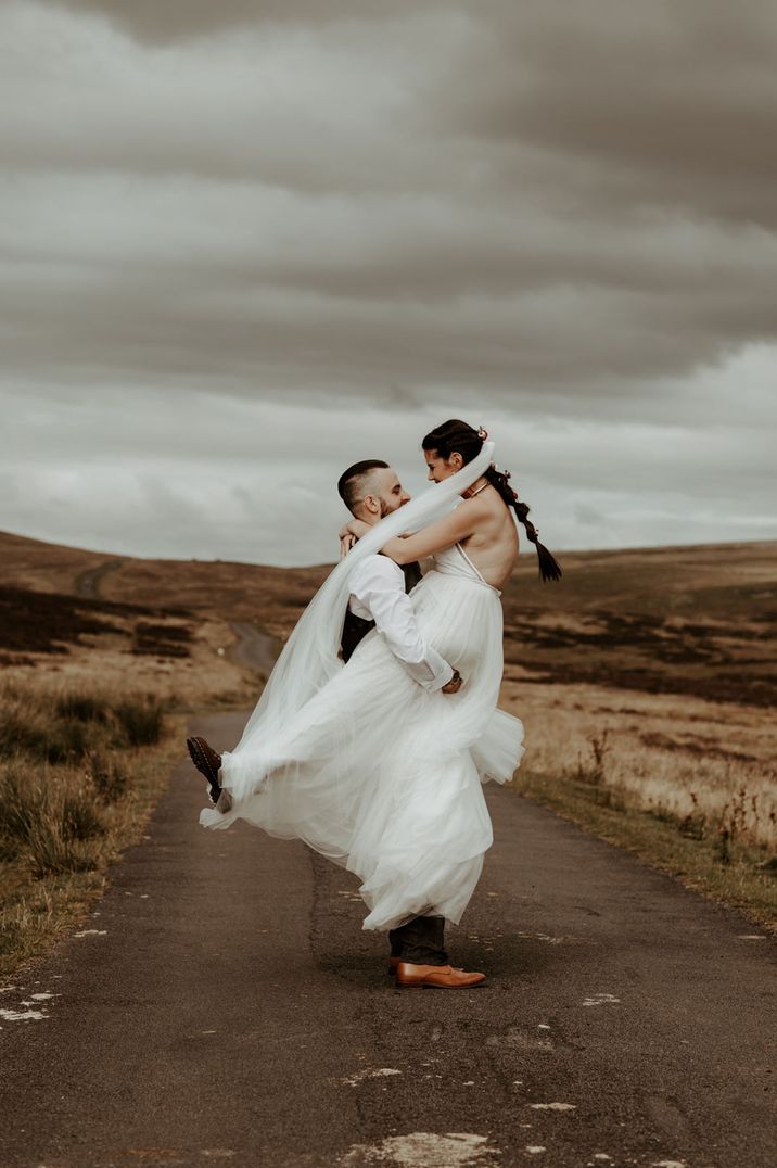 Bride and groom embracing in wedding attire and boots at socially distanced Eden Barn wedding