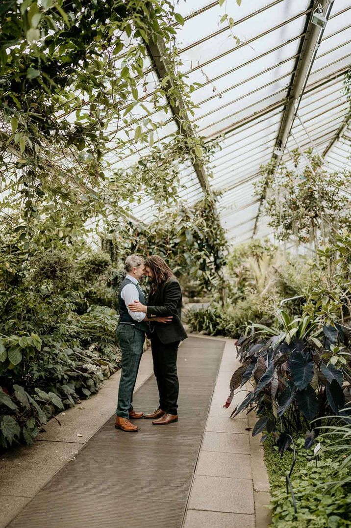 Grooms embracing in Kew Gardens London greenhouse 