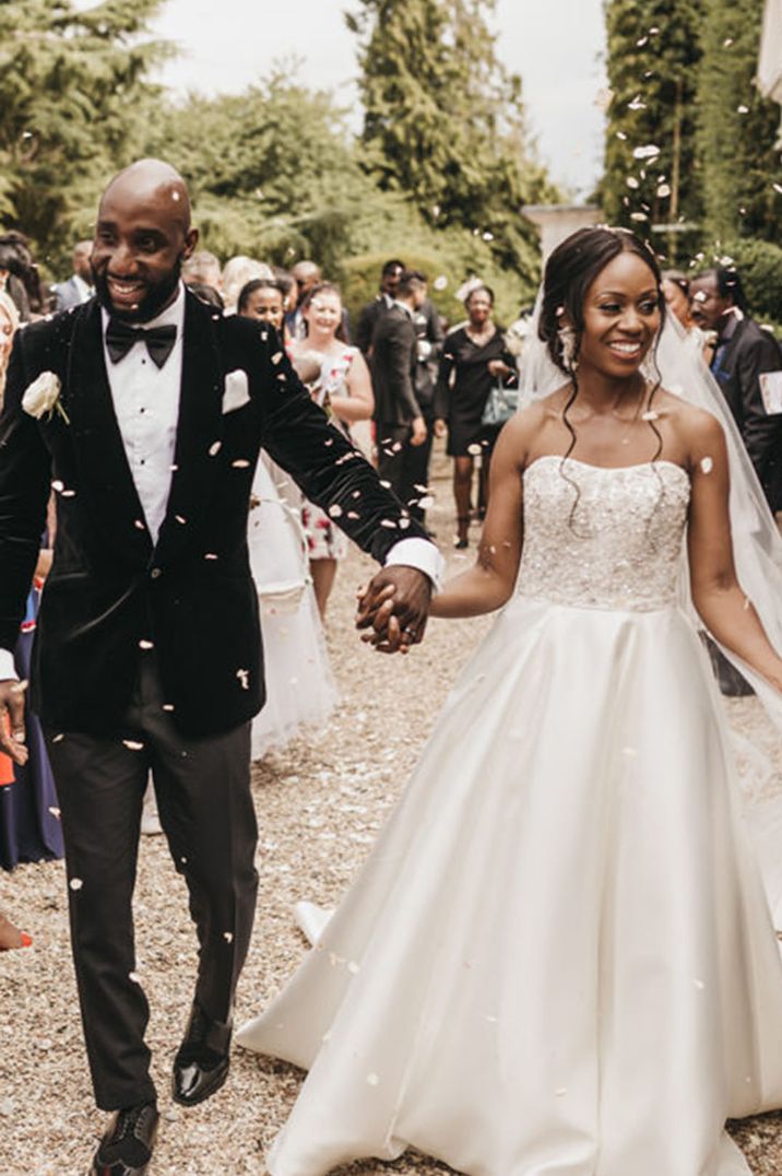 Bride in a strapless embellished Oleg Cassini princess wedding dress has confetti moment with the groom in black tie 