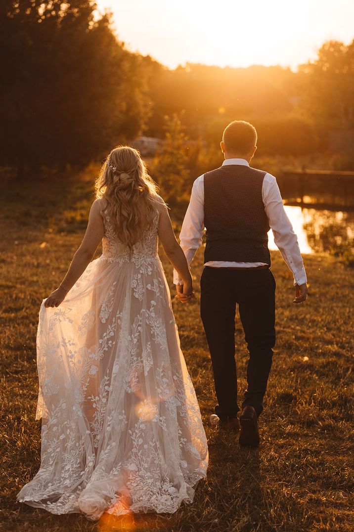 Golden hour wedding photography of the bride and groom walking together 