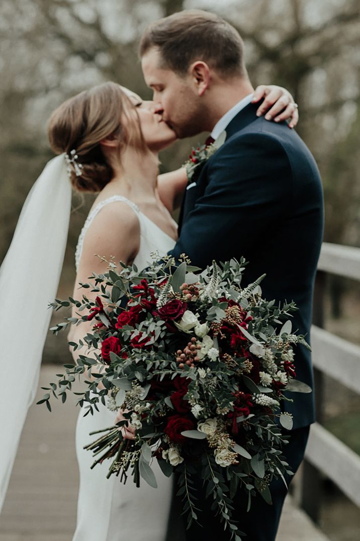 Large oversized cascading wedding bouquet made up of winter wedding flowers and red roses 