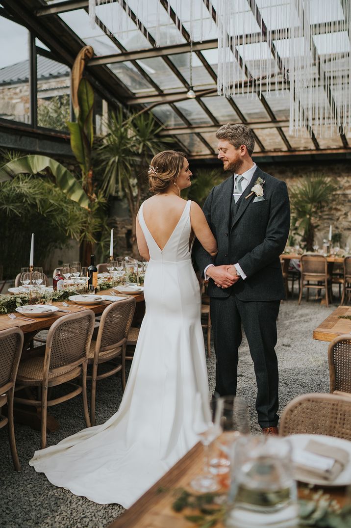 Bride in dropped waist wedding gown standing with groom at glasshouse wedding 