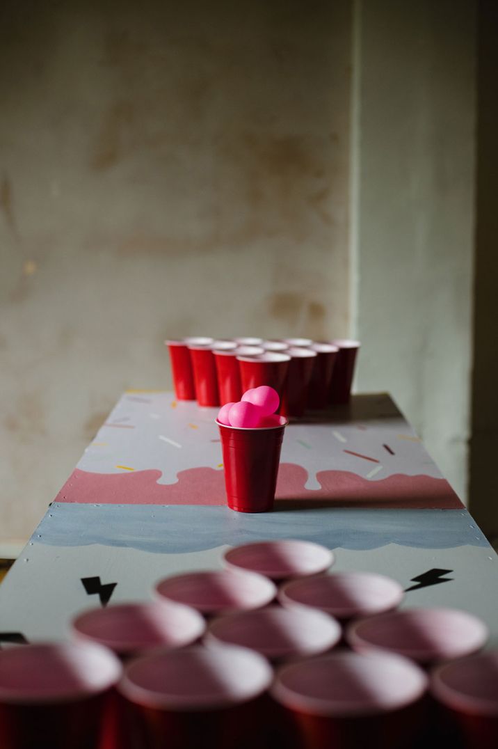 Red solo cups on a table with pink ping pong balls for a game of beer pong 