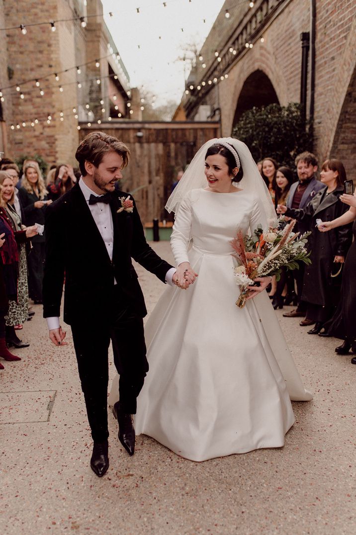 Newlyweds walk hand in hand together in front of wedding guests at LGBTQI+ wedding