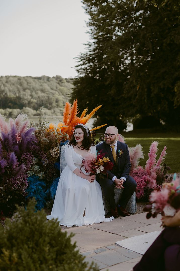 Bright pampas grass altar decoration with bride and groom seated in front of them 