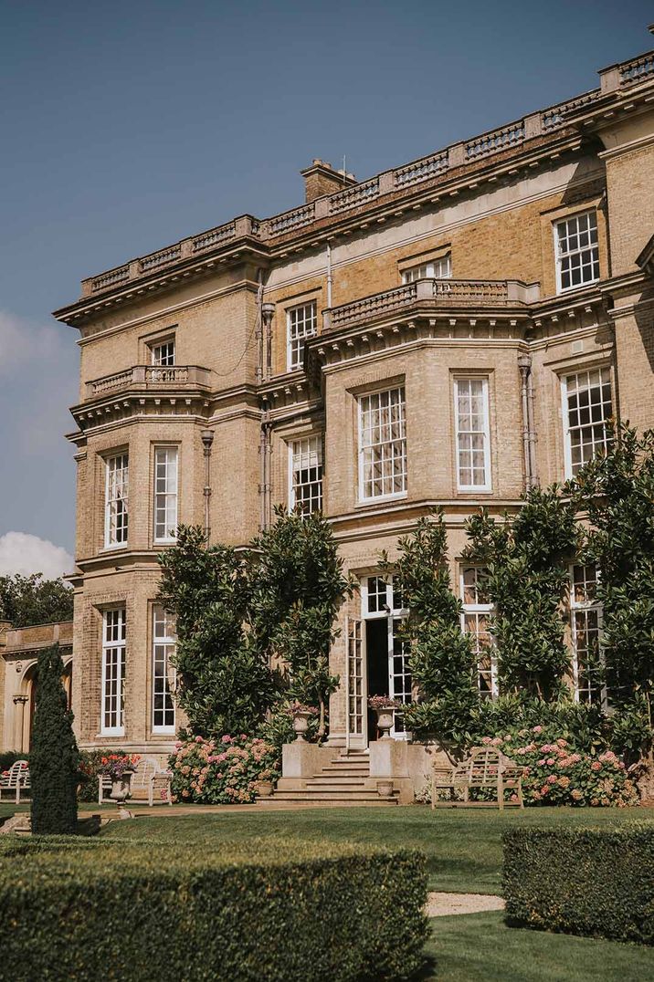 The exterior and grounds of country house wedding venue with blue skies and lush foliage