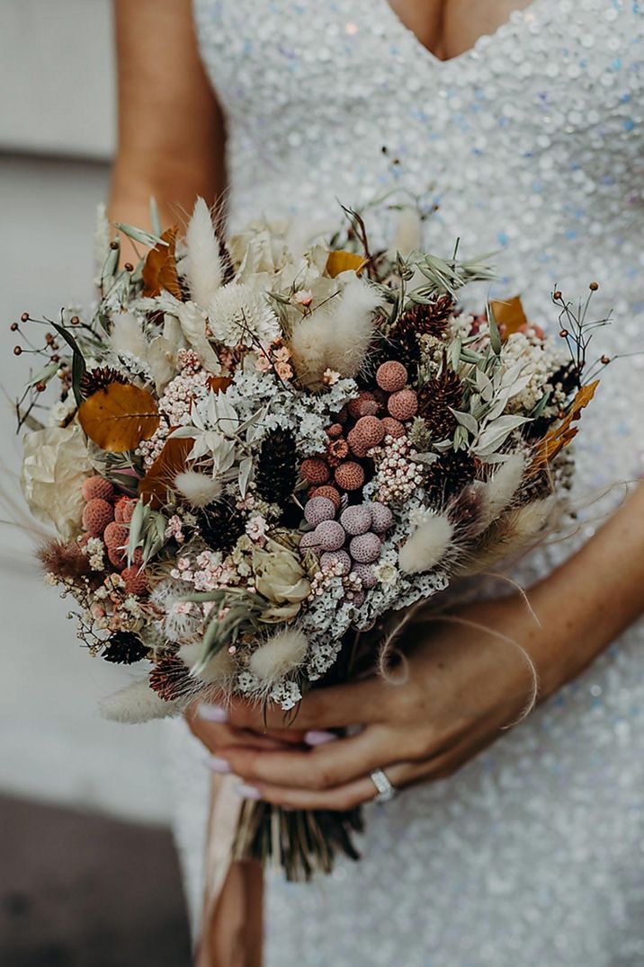 Bride holding mixed dried flower wedding bouquet 