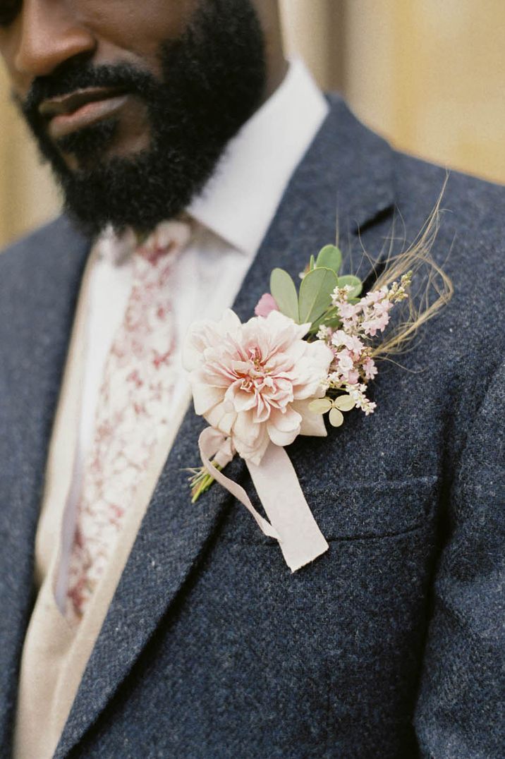 Groom in navy suit with pink rose buttonhole and pink patterned tie 