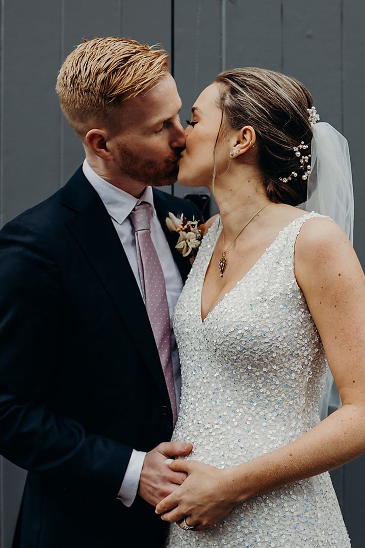 The bride and groom share an intimate kiss as the groom places his hand on the bride's baby bump 