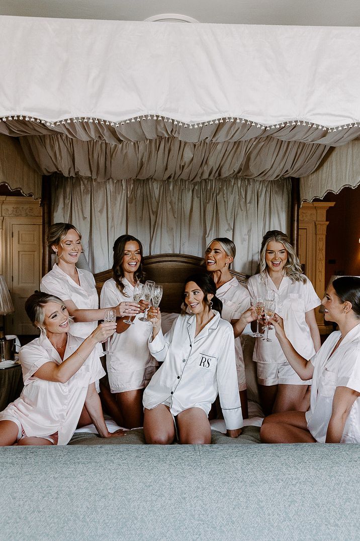 Bridal party sitting on a bed posing for group photos as they get ready together 