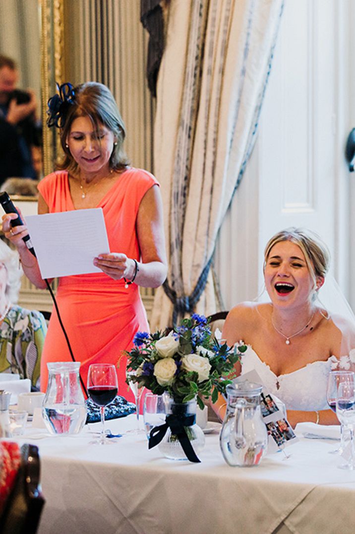 Bride sitting down at the wedding breakfast with the mother of the bride reading her wedding speech 