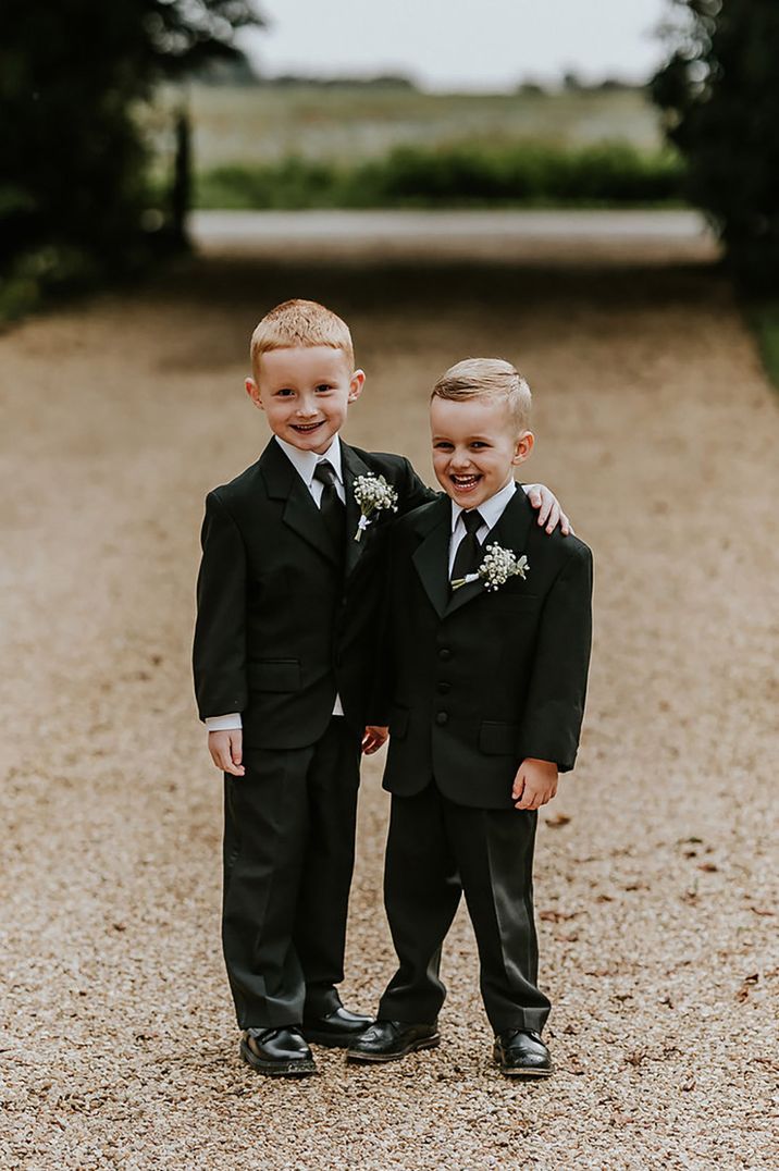 Two page boys wearing black wedding suits with white gypsophila buttonholes 