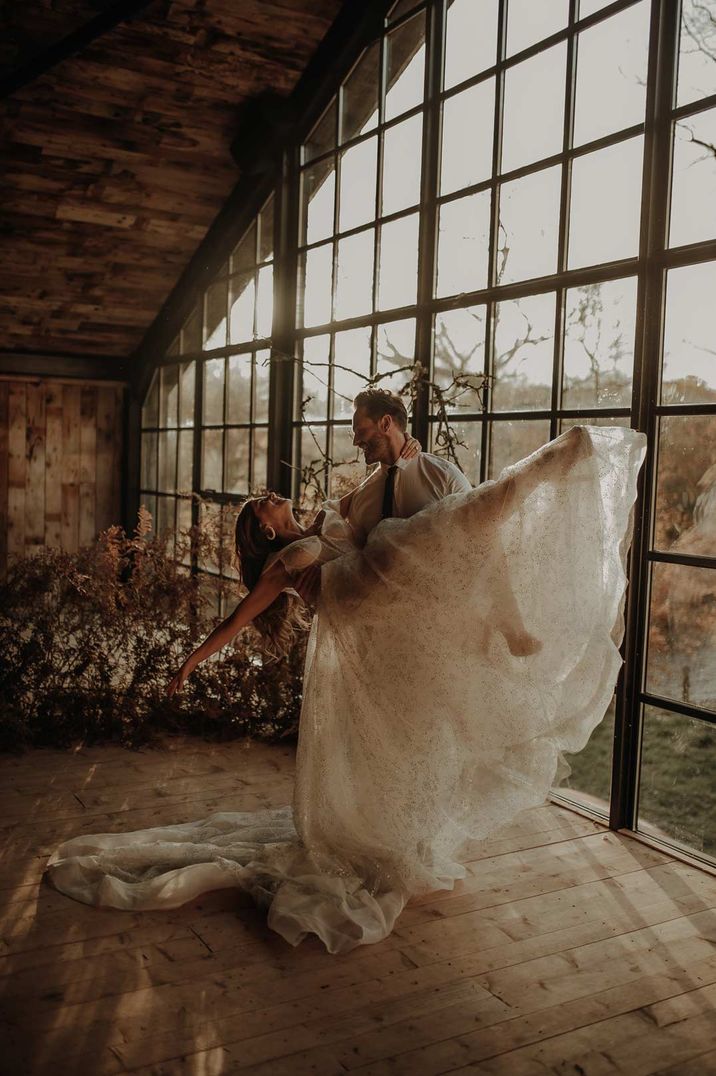 Groom lifting bride in glitter embellished full wedding dress at Hidden River Cabins