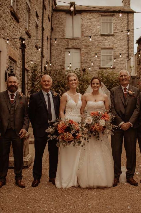 Wedding party standing in the courtyard of Holmes Mill, unusual wedding venues