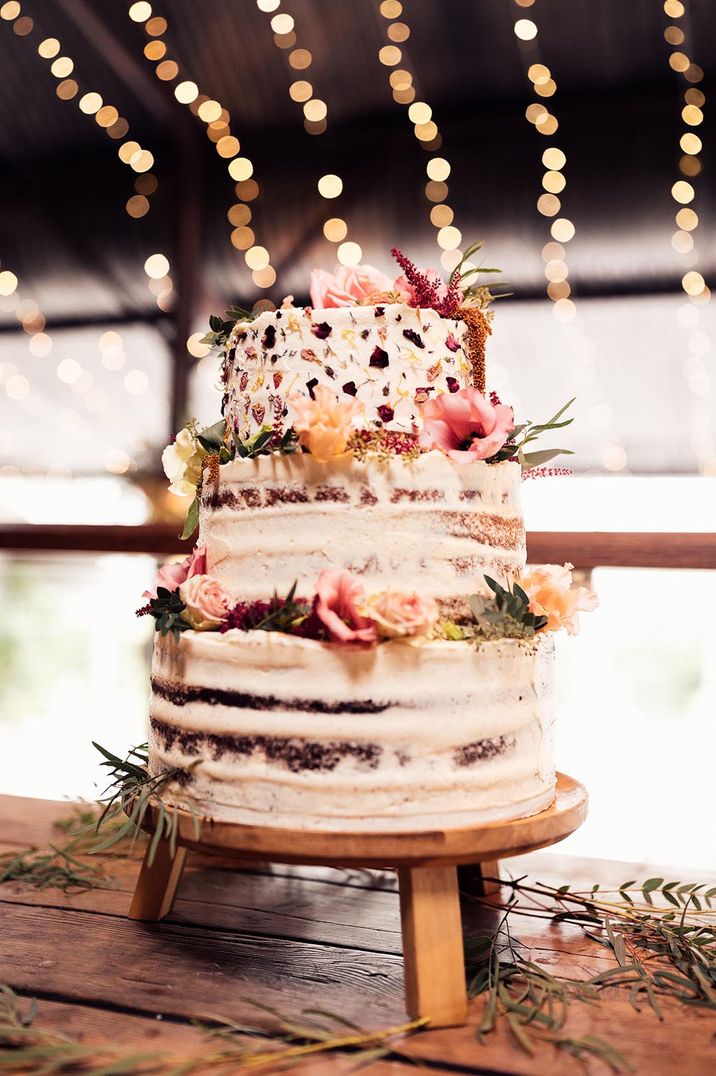 Three tiered buttercream wedding cake with printed florals and flower decorations at barn wedding venue