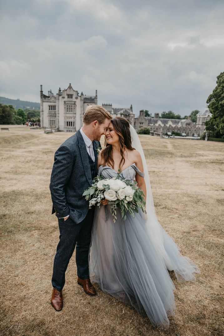 Bride in blue tulle wedding dress kissing the groom in a tweed suit at their Irish wedding 