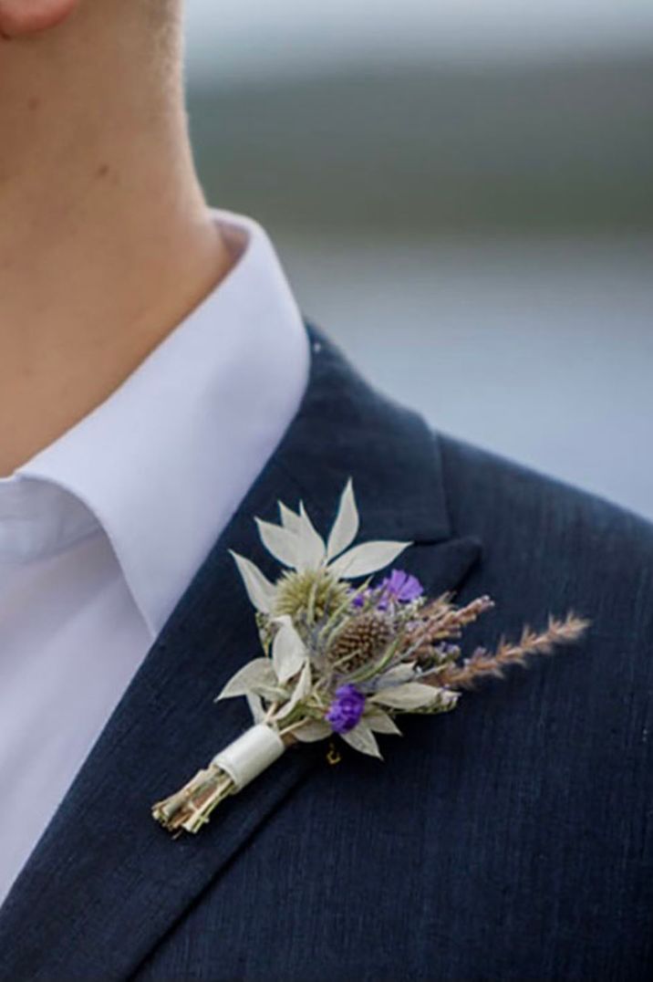 A dried flower wedding buttonhole worn by the groom so it can also act as a wedding keepsake 