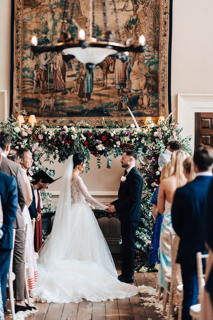 Bride in long sleeve lace wedding dress holding hands with the groom at their wedding ceremony at Elmore Court 