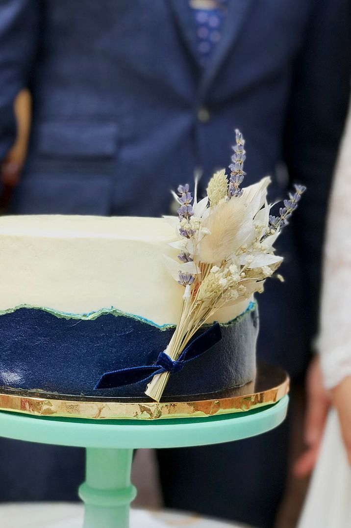 Dried flowers tied to side of white and navy wedding cake