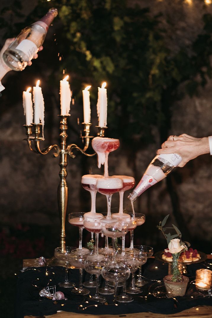 Two grooms pouring pink champagne into a champagne tower 