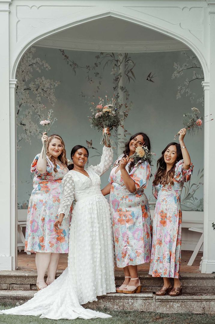 Bride in polka dot detailed appliqué wedding dress and bridesmaids in matching floral dresses at Wasing Park