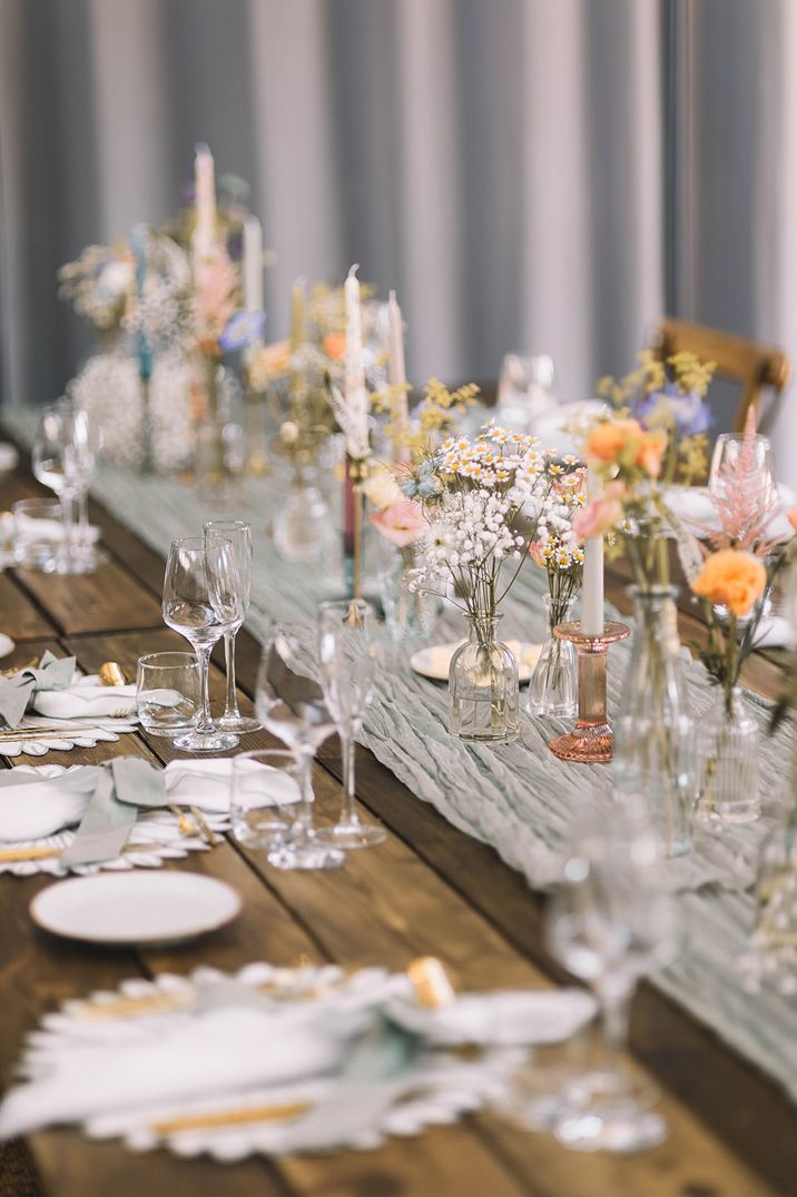 Pastel wedding theme tablescape with green table runner and handpainted candles 