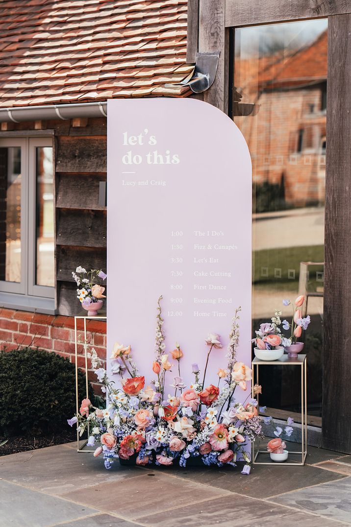 Lilac coloured wedding signage decorated with pastel wedding flowers 