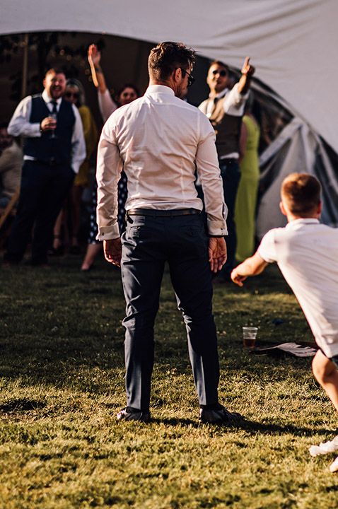 The young boys at the wedding play a game of football outside the marquee 