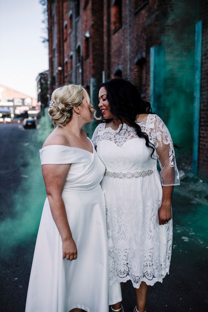 Brides lean in for a kiss with a green smoke bomb for their Liverpool city wedding 